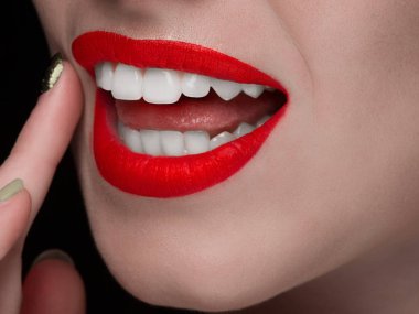 Yakın çekim alt kısmındaki yüzün bembeyaz bir gülümseme ile güzel bir kadının portresi. Dokun ve cilt bakımı. Dudaklarında kırmızı kırmızı ruj. Beyaz gülümseme beyaz dişler, diş hekimliği ile