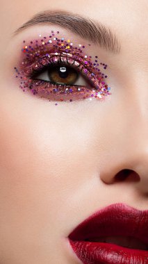 Bir kadının yarım yüz güzelliği sparkles yaratıcı moda makyaj ile Close-up. Siyah eyeliner ve uzun kirpiklerini ela gözlü ve dudakları eşleşecek şekilde süsleyin. Spa sonra bakımlı cilt