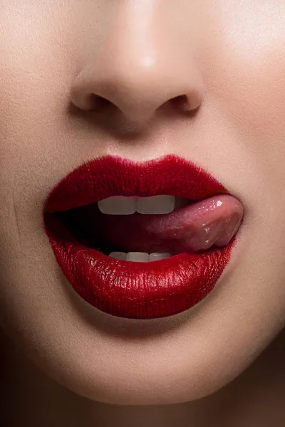 Seksi kadın dudak dil ile yakın çekim. Temiz cilt ve açık dudak kontur moda kırmızı ruj ile özetlenmiştir. Beyaz dişler ve bir gülümseme stamotologii, spa veya kozmetik güzellik