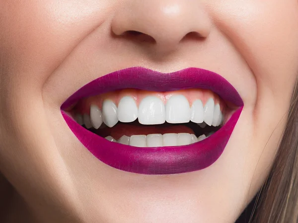 Close-up shot of sexy woman\'s lips with pink lipstick and clean skin. Beautiful spa portrait with a snow-white smile. Spa and cosmetics, dentistry and cosmetology, teeth extraction