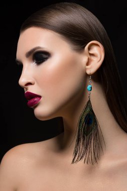 Marsala ruj ve moda tavus kuşu tüyü küpe ölümcül makyaj vurgulayan bir ryunette kadının muhteşem yüz özellikleri, güzelliği bir yakın çekim portre sihir görüntüye ekler.