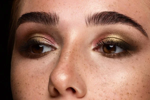 Close-up dos olhos da mulher com maquiagem à noite. Sombras na moda de sombra de olho, pestanas extremamente longas e sobrancelhas lisas grossas. Abra o olhar bonito. Pele limpa e sardas no rosto — Fotografia de Stock