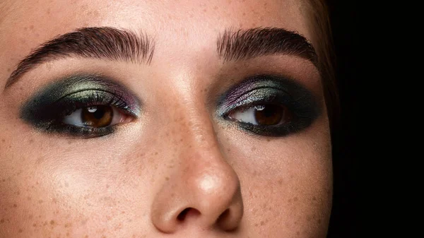 Close-up dos olhos da mulher com maquiagem à noite. Sombras na moda de sombra de olho, pestanas extremamente longas e sobrancelhas lisas grossas. Abra o olhar bonito. Pele limpa e sardas no rosto — Fotografia de Stock