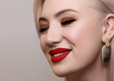 Düz saçlı ve tamamen temiz tenli güzel bir kadının yakın plan portresi. Akşam makyajı, stil ve kulaklarda zarif süslemeler. Küpeler. Spa salonunda cilt bakımı ya da kozmetoloji gülümsemesi.