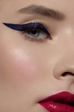 Güzel bir akşam makyajıyla yarım bir güzellik portresi, gözlerde siyah titreşimler ve son derece uzun kirpiklerle. Dudaklarında pembe ruj izi var. Kozmetik ve kaplıca cilt bakımı