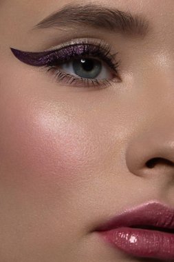 Güzel bir akşam makyajıyla yarım bir güzellik portresi, gözlerde siyah titreşimler ve son derece uzun kirpiklerle. Dudaklarında pembe ruj izi var. Kozmetik ve kaplıca cilt bakımı