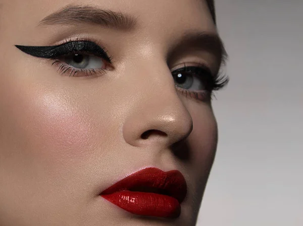 Ein Nahaufnahme-Porträt der Schönheit mit wunderschönem modischem Abend-Make-up, schwarzen Fallen auf den Augen und extrem langen Wimpern. roter Lippenstift auf den Lippen. Kosmetologie und Wellness Gesichtspflege — Stockfoto