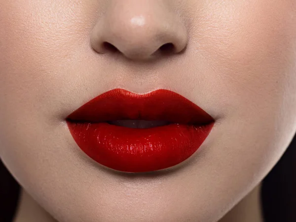 Cosmetici, trucco e tendenze. Brillante lucidalabbra e rossetto sulle labbra. Primo piano di bella bocca femminile con trucco labbra rosse. Bella parte del viso femminile. Pelle pulita perfetta a luce rossa — Foto Stock