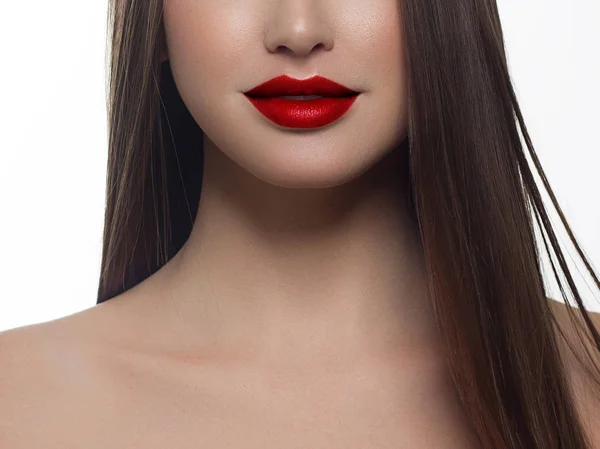 Cosméticos, maquillaje y tendencias. Brillo labial brillante y lápiz labial en los labios. Primer plano de hermosa boca femenina con maquillaje de labio rojo. Hermosa parte de la cara femenina. Piel limpia perfecta en luz roja — Foto de Stock