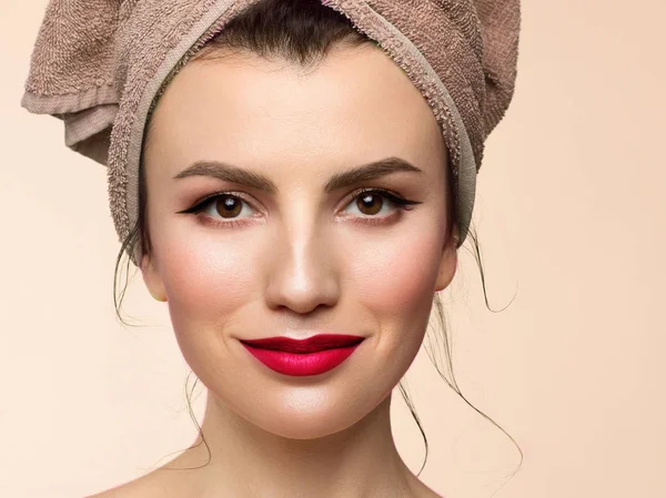 Beauty girl closeup with evening make-up. A woman looks into the camera with a slight grin with a towel on her head. Clean skin after spa treatments. Red sensual lips and arrows on the eyes