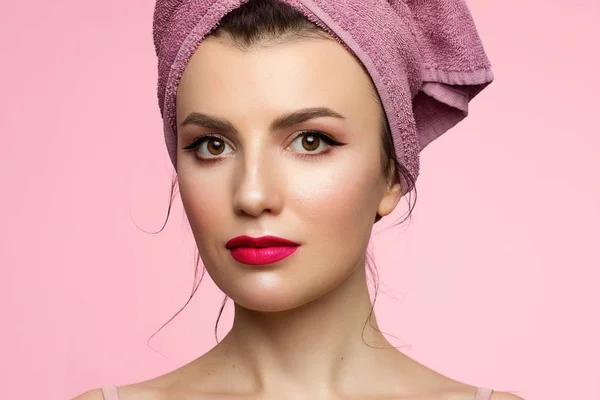 Mulher beleza rosto com as mãos. Linda modelo de Spa Retrato Menina com Pele Fresca Perfeita Limpa. Mulher olhando para a câmera e sorrindo. Conceito de Cuidados da Juventude e da Pele. Toalha rosa na cabeça, espaço para texto — Fotografia de Stock