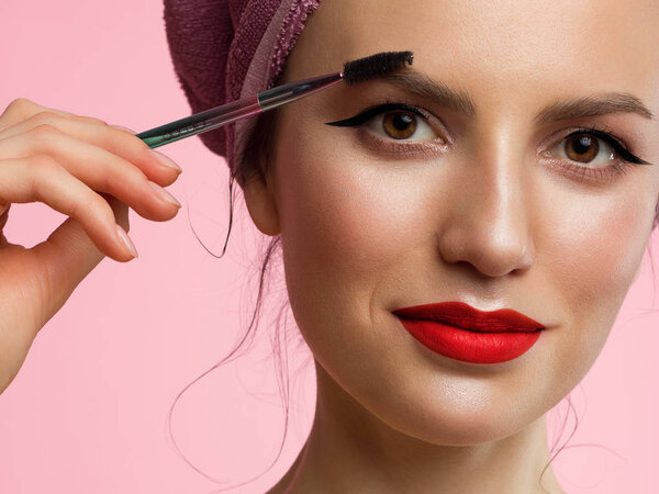 Крупный план красивой женщины с классическим макияжем и чистой кожей. Черная подводка для глаз и красные губы. Чистящие густые брови. Косметология и спа
