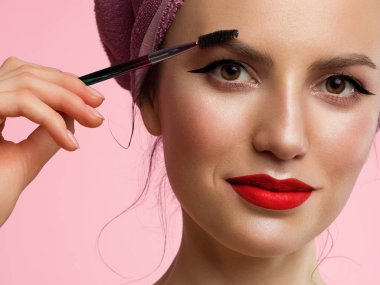 Klasik makyajve berrak bir cilde sahip güzel bir kadının yakın çekim. Gözlerde ve kırmızı dudaklarda siyah göz kalemi. Kalın kaşları taramak. Kozmetoloji ve spa