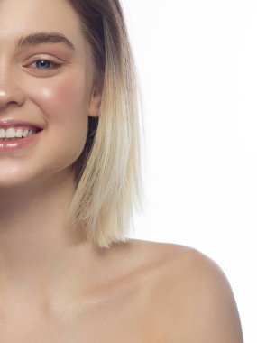 Kameraya gülümseyen güzel bir kadının yarısı yakın çekim portresi. Kısa saç kesimi ve doğal makyaj. Beyaz dişleri ile mutlu bir gülümseme. Spa ve kozmetoloji, diş hekimliği