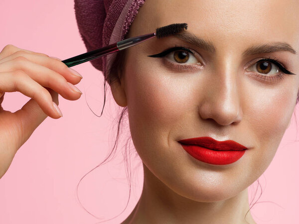 Крупный план красивой женщины с классическим макияжем и чистой кожей. Черная подводка для глаз и красные губы. Чистящие густые брови. Косметология и спа
