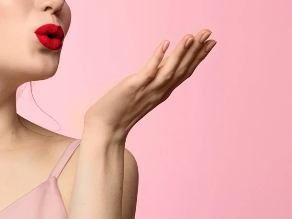 Primo piano di labbra paffute sensuali con rossetto rosso cosparso di un bacio d'aria su uno sfondo di letto rosa. Bellezza ed eleganza, mani con manicure naturale — Foto Stock