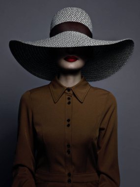 Dudaklarında kırmızı ruj ve büyük bir şapka ile güzel kadın portre. Gizemli bir kızın vintage görüntüsü. Moda makyaj ve giysi. Şapka yüzün yarısını kaplıyor. Gri arka plan