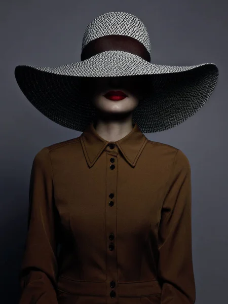 Piękna kobieta portret z czerwoną szminką na ustach i wielkim kapeluszem. Vintage wizerunek tajemniczej dziewczyny. Modny makijaż i ubrania. Kapelusz pokrywa połowę twarzy. Szare tło — Zdjęcie stockowe