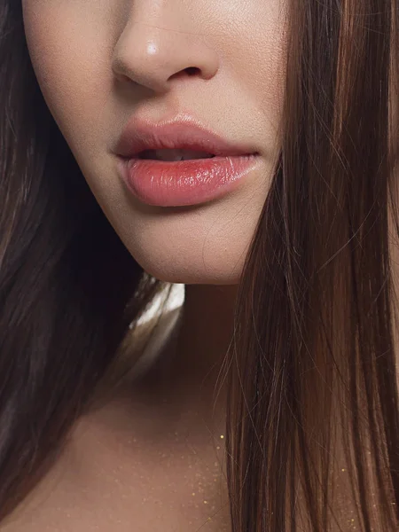 Beauty closeup of women full red lips with shiny skin and long hair. Facial skin care in a spa salon or cosmetology and a fashionable natural lip gloss or lipstick. Day makeup