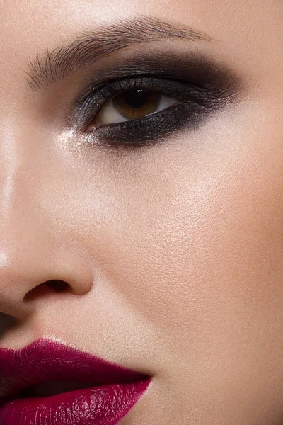 Close-up da beleza do rosto de uma mulher com maquiagem à noite enfatizando suas características faciais expressivas. Olhos fumegantes, lábios cor de marsala e pele clara. Em um fundo preto isolado — Fotografia de Stock