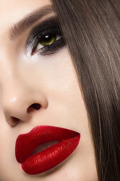 Close-up van de schoonheid van het gezicht van een halve vrouw met mode-avondmake-up. Zwarte rokerige ogen en lange wimpers, op gezwollen lippen matte lippenstift kleur wijn. Schone huid na spa en lang haar. Rode lippen — Stockfoto