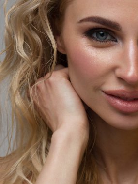 Düz saçlı, kusursuz ciltli, yarı güzel bir kadının yakın plan portresi. Gündüz makyajı, tasarım ve kulaklarda zarif süslemeler. Küpeler. Spa salonunda cilt bakımı ya da kozmetoloji gülümsemesi.