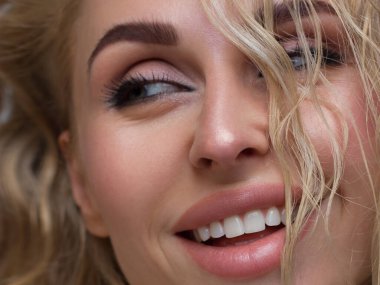 Parlak makyajlı, seksi siyah makyajlı güzel bir kadın. Kadınların göz kapaklarında büyük ok şeklinde moda. Doğal dudaklar. Şık bir akşam makyajı. Sarışın, uzun dalga saçlı. Parlak yüz derisi