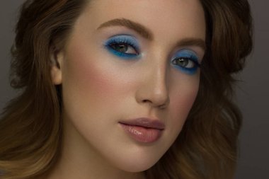 Yarım bir kadının yüzünün güzelliğine yakın çekim yaratıcı modaya uygun ışıltı makyajıyla. Siyah göz kalemi ve uzun kirpikler ela gözleri ve dudakları uyumlu hale getirir. Kaplıcadan sonra iyi bakımlı cilt