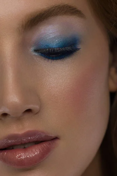 Close-up schoonheid van een half gezicht van een vrouw met natte stralende huid en grote grijze ogen. Modieuze avondmake-up en nat gezichtshaar. Roze lippenstift met gezoende lippen — Stockfoto