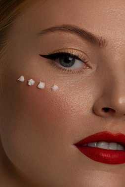 Yaratıcı moda gecesi makyajlı, yarı kadın yüzünün yakın plan güzelliği. Gözlerde siyah oklar ve son derece uzun kirpiklerde, dolgun dudaklarda kırmızı dudak rengi. Kaplıcadan sonra iyi bakımlı cilt