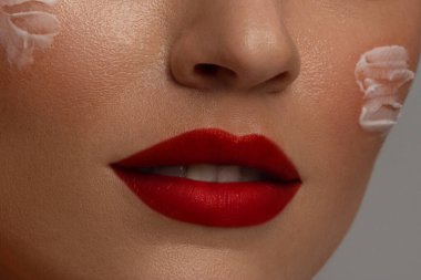 Mükemmel kırmızı dudak macunu. Güzel bir kadın ağzıyla makro kesilmiş fotoğraf, sağlık, tedavi, terapi konsepti, gri arka planda izole edilmiş.