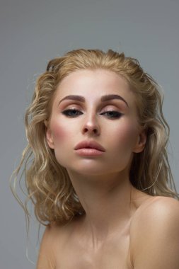 Parlak makyajlı, seksi siyah makyajlı güzel bir kadın. Kadının göz kapağında büyük bir ok şekli var. Doğal dudaklar. Şık bir akşam makyajı. Lüks uzun dalga saçı. Parlak yüz derisi
