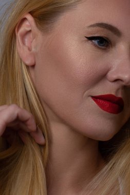 Yaratıcı moda gecesi makyajlı, yarı kadın yüzünün yakın plan güzelliği. Gözlerde siyah oklar ve son derece uzun kirpiklerde, dolgun dudaklarda kırmızı dudak rengi. Kaplıcadan sonra iyi bakımlı cilt