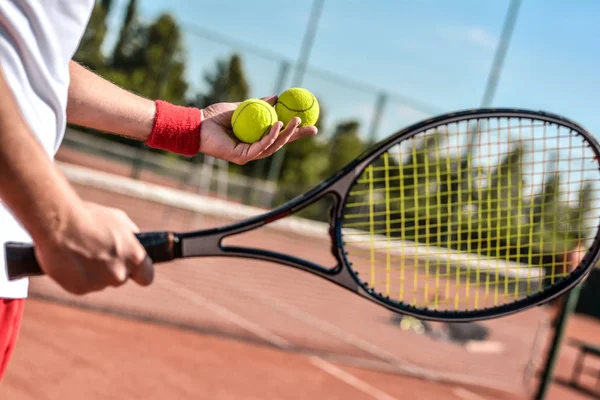 テニスコートで若い男の写真を閉じます テニス男 男はテニス ボールを投げる準備ができています 背景として美しい森林面積 — ストック写真