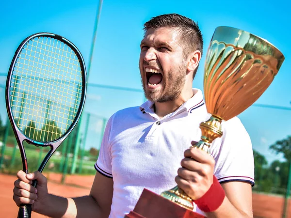 Happy male tennis player with goblet and racket after match