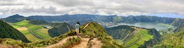 Genç çift Azores, Sao Miguel 'deki Pico da Cruz' dan Krater Sete Cidades 'in panoramik manzarasının tadını çıkarıyor.