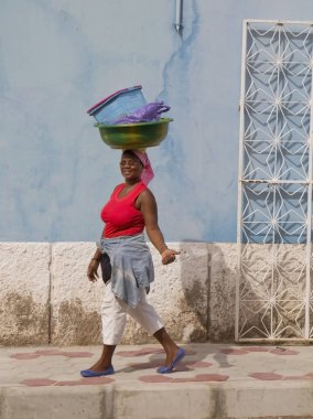 Mindelo, Cape Verde, Afrika, 12/07/2012, kent sakinlerinin. Mindelo Cape Verde ikinci en büyük şehridir. Genç kadın bir havza ile şehirde kafasına yürür.