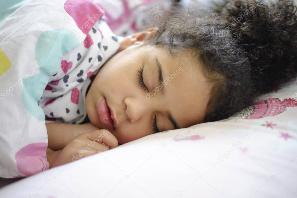 Little African American girl sleeping in bed