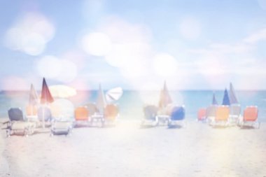 Şemsiye ve şezlong ile kumlu plaj manzara bulanık görüntü.