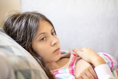 Genç kız yatakta yatıp sıcaklığı kontrol ediyor.