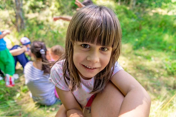 在森林里玩耍的小女孩 背景上的家人和朋友 — 图库照片