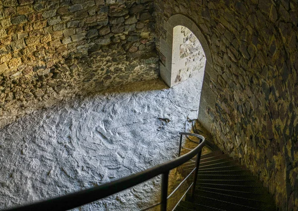 Edifício de pedra antigo, escada sinuosa, vista da saída através da qual a luz brilha — Fotografia de Stock