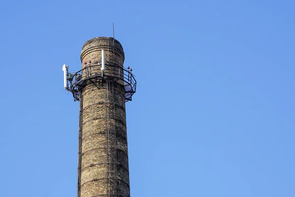 a chimney with electronic communications equipment on it against a blue sky