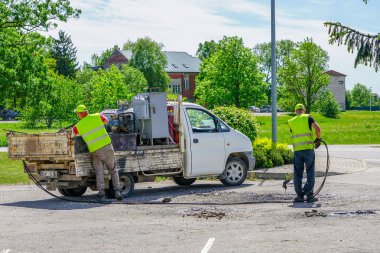 Yol işçileri yolda çukurları onarmak için sıcak asfalt koyuyor
