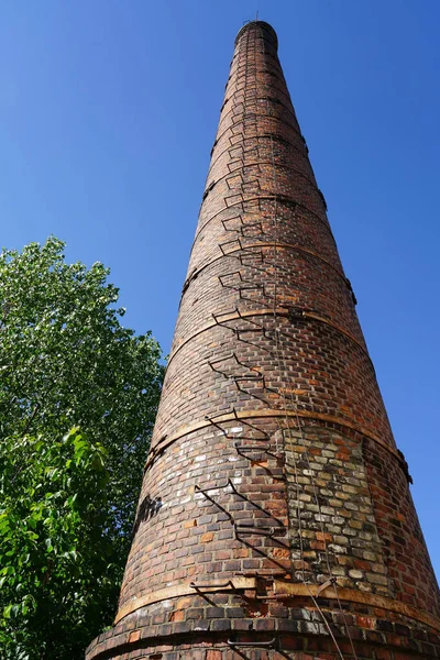 Stary wysoki komin fabryczny przeciw błękitnym niebem. — Zdjęcie stockowe
