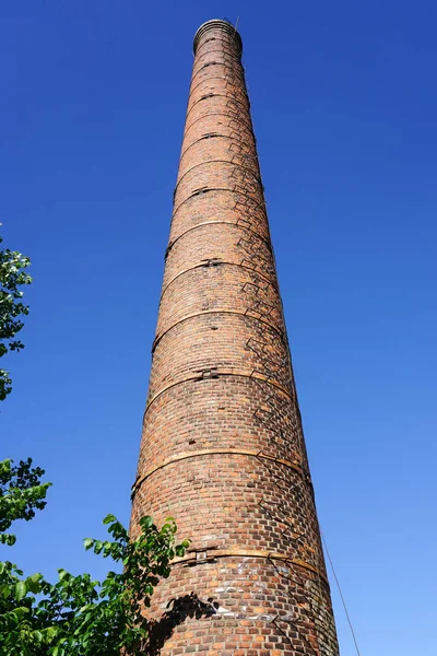 Stary wysoki komin fabryczny przeciw błękitnym niebem. — Zdjęcie stockowe