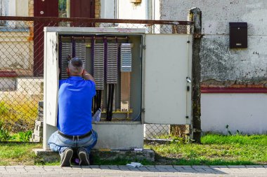Teknisyen sokaktaki terminal bloğundaki telekomünikasyon sitelerini kontrol ediyor.
