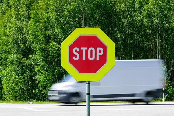 Red stop road sign in the foreground and blurred fast car in the background — Stock Photo, Image