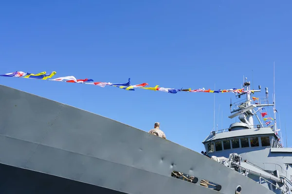 Ένα γκρίζο θραύσμα πολεμικό, διακοσμημένο με μια σειρά από πολύχρωμες ναυτικές σημαίες — Φωτογραφία Αρχείου