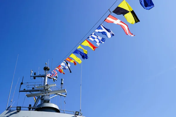 Ένα γκρίζο θραύσμα πολεμικό, διακοσμημένο με μια σειρά από πολύχρωμες ναυτικές σημαίες — Φωτογραφία Αρχείου